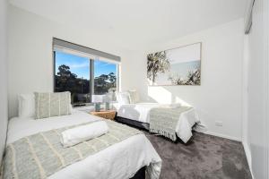 a bedroom with two beds and a large window at The Bay Townhouse 500m to beach 15min to CBD in Hobart