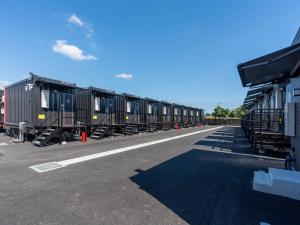 una fila di vagoni ferroviari parcheggiati in un parcheggio di HOTEL R9 The Yard Ishioka a Ishioka