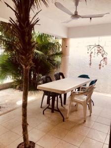 a table and chairs in a patio with a palm tree at Casa yuya in Chicxulub