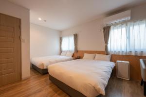 IshiokaにあるHOTEL R9 The Yard Ishiokaのベッド2台と窓が備わるホテルルームです。