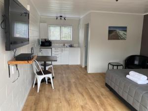 a bedroom with a bed and a desk and a kitchen at Wayfarer Motel in Kaitaia