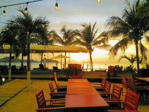 un grupo de mesas y sillas en una playa con puesta de sol en Hotel Tabasco en Playa Flamingo