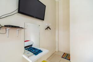 ein Wohnzimmer mit einem TV an der Wand in der Unterkunft RedDoorz Syariah near Pasar Aur Kuning in Bukittinggi