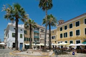 a city street with palm trees and tables and buildings at Villa Siena by Villa Plus in Cala en Blanes