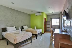 a bedroom with two beds and a desk and a television at Boonme Heritage in Phitsanulok
