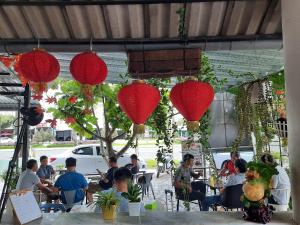 Ấp Thới Thuận (4)的住宿－Khách sạn Hoàng Mai，一群坐在红色灯笼下的桌子上的人