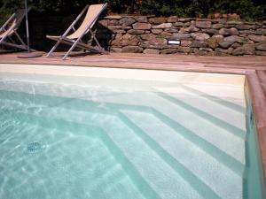 a swimming pool with two lawn chairs next to a wooden deck at Belvilla by OYO Mulino in Cortona