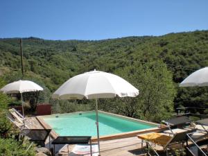 a swimming pool with two umbrellas and a table and chairs at Belvilla by OYO Mulino in Cortona