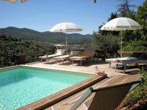 a swimming pool with chairs and umbrellas on a deck at Belvilla by OYO Mulino in Cortona