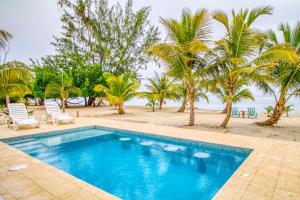una piscina junto a una playa con palmeras en Tres Palmas Beach House, en Maya Beach