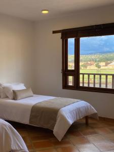 a bedroom with a bed and a large window at Hotel Alandalus in Villa de Leyva