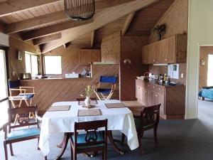 una sala da pranzo con tavolo e sedie bianchi di Waiotemarama Falls Lodge a Opononi
