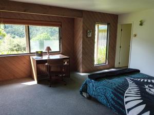 een slaapkamer met een bureau, een bed en een bureau bij Waiotemarama Falls Lodge in Opononi