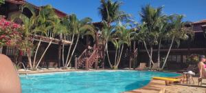 a swimming pool in front of a building with palm trees at Geribá Apart Hotel Internacional Buzios in Búzios
