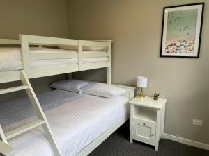 a bedroom with two bunk beds and a table with a lamp at Pauanui Lakes - Golf Resort in Pauanui +25 photos