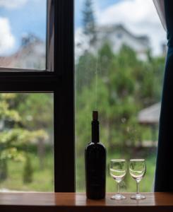 a bottle of wine and two glasses on a window at The K'rin Villa in Da Lat