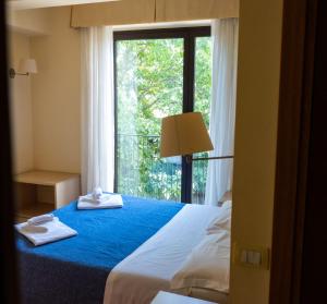 ein Schlafzimmer mit einem großen Fenster und Handtüchern auf einem Bett in der Unterkunft Hotel Milomax in Milo