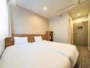 a bedroom with a large bed with white sheets at Tabist Ginza in Tokyo