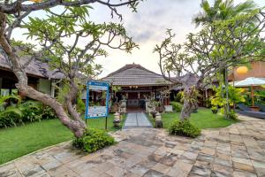 a house with a patio and trees in front of it at Desamuda Village in Seminyak