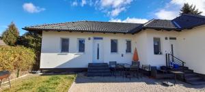 a white house with chairs and a roof at Rigó Apartman in Keszthely