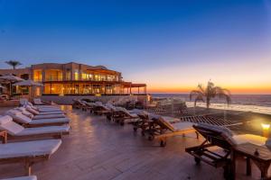 a resort with lounge chairs and the ocean at sunset at Cleopatra Luxury Resort Sharm El Sheikh in Sharm El Sheikh