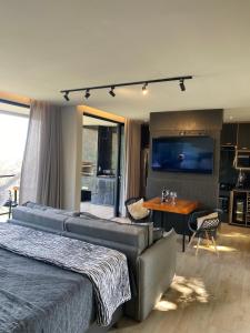 a bedroom with a couch and a table and a television at Loft Paraíso Da Serra in Congonhas
