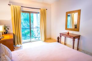 a bedroom with a bed and a mirror and a window at Paseo del Sol Condohotel by BVR in Playa del Carmen