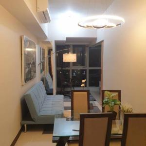 un soggiorno con divano e tavolo in vetro di Cozy 1BR UPTOWN PARKSUITES Tower1 BGC a Manila