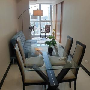 uma mesa de jantar com cadeiras e uma mesa de vidro com uma planta em Cozy 1BR UPTOWN PARKSUITES Tower1 BGC em Manila