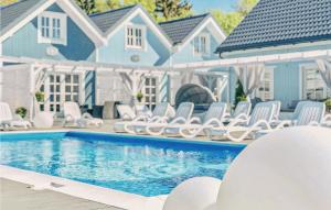 a swimming pool with white chairs next to a house at Cozy Home In Mielno With Wifi in Mielno