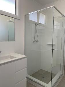 a glass shower in a bathroom with a sink at Busselton Jetty Chalets in Busselton +21 photos