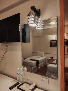 a hotel room with two beds and a mirror at Asia Grand Hotel in Hat Yai