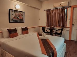 ein Hotelzimmer mit 2 Betten, einem Tisch und einem Fenster in der Unterkunft Asia Grand Hotel in Hat Yai