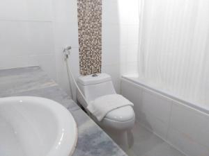 a white bathroom with a toilet and a sink at Merlin Grand Hotel in Hat Yai