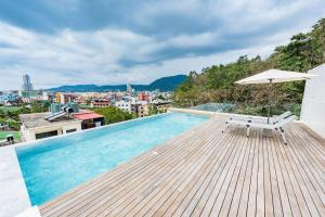 a swimming pool with a chair and an umbrella at LullaBella Hotel in Patong Beach