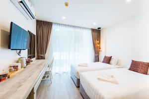 a hotel room with two beds and a flat screen tv at LullaBella Hotel Patong,Nanai Road in Patong Beach