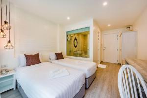two beds in a small room with a window at LullaBella Hotel Patong,Nanai Road in Patong Beach
