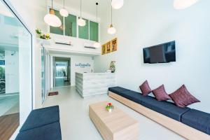 ein Wohnzimmer mit einem Sofa und einem TV in der Unterkunft LullaBella Hotel in Patong Beach
