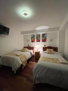 a bedroom with two beds and a tv on the wall at Hotel Choquequirao in Cusco