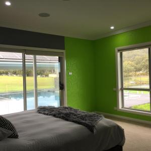 a bedroom with green walls and a bed and windows at ON Keppies - BnB - Family Farm & Wedding Guest Accommodation Paterson NSW in Paterson