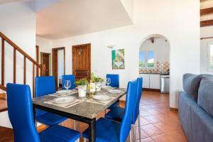 Villa Vientosol by Villa Plus في كالا ان فوركات: غرفة طعام مع طاولة وكراسي زرقاء