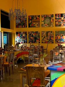 un restaurante con mesas, sillas y pinturas en la pared en Buckingham Place, en Tangalle