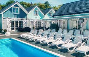 a pool with chaise lounge chairs next to a house at Stunning Home In Mielno With Wifi in Mielno