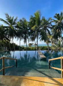 a swimming pool with palm trees and a view of the ocean at Buckingham Place in Tangalle