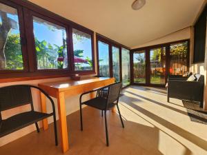 a room with a wooden table and chairs and windows at House & Yard Sesil M 110m to beach in Ureki