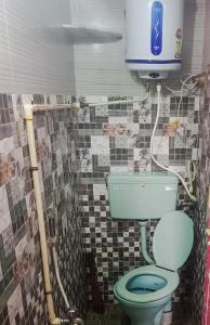 a bathroom with a green toilet and a tv at Sai Homestay in Kanchipuram