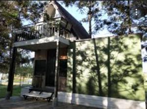 a building with a balcony and a bench in front at The O'clock Farmstay Khaokor in Khao Kho