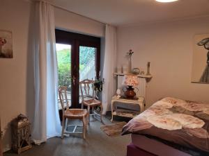 a bedroom with a bed and two chairs and a balcony at Auszeit an der Nordsee in Husum