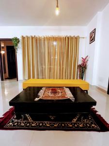 a yellow bench in a living room with a curtain at Luxurious 3BHK vacation home amidst the city. in Mangalore