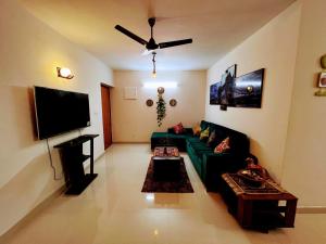 a living room with a green couch and a flat screen tv at Luxurious 3BHK vacation home amidst the city. in Mangalore